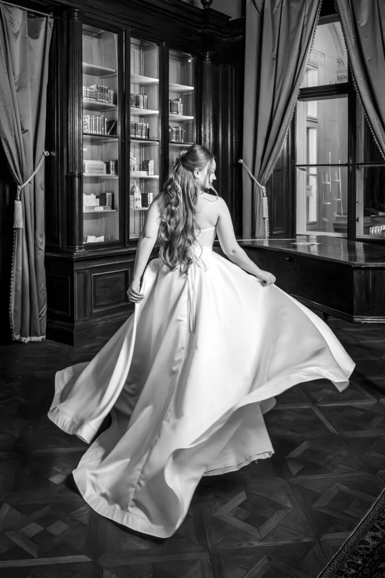A menyasszony megpördíti szoknyáját a kastély egyik termében gszszfoto
